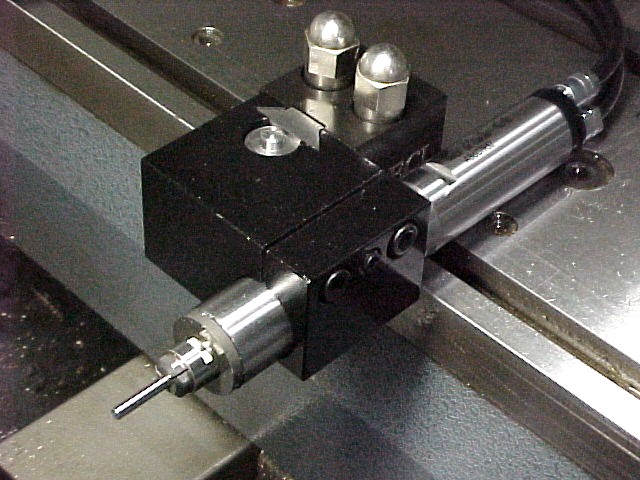 Metalworking tool with long rod and two spheres on a metal surface.