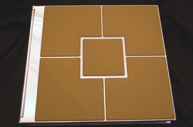 A tan-covered book with geometric design featuring six square panels in two rows on a black surface.