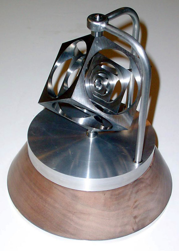 Polished silver metal sculpture of a cube with wooden base featuring three-dimensional rings in artistic arrangement.