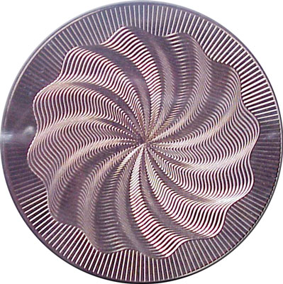 Circular metal plate with guilloche pattern of wavy, symmetrical lines resembling flower or shell shape.