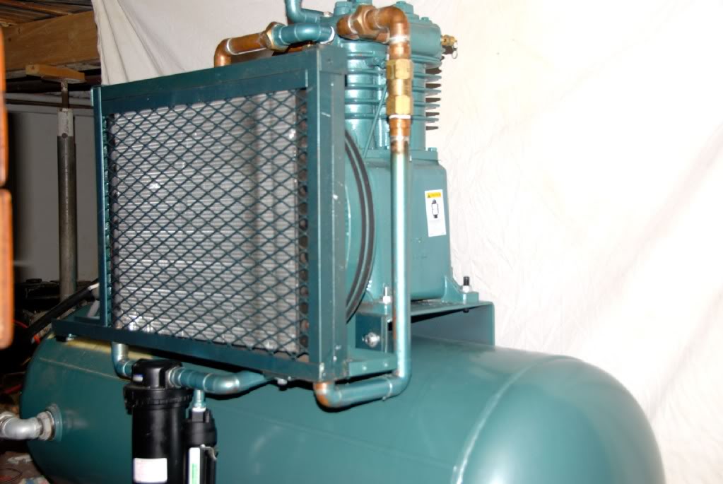 Green air compressor aftercooler with protective guard.