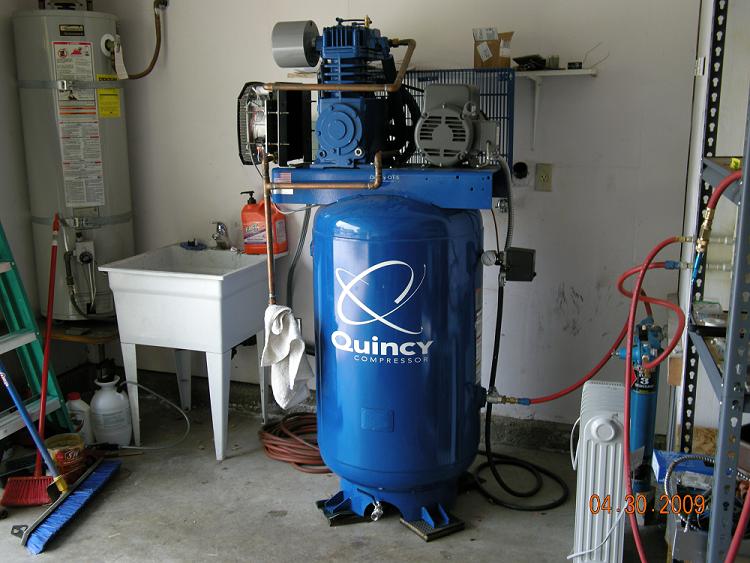 Garage workshop with blue air compressor and assorted tools.