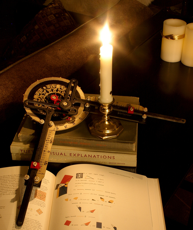 A photograph of an ideal harmonic transformer with a candle on top, sitting on books including "Visual Explanations" and "The Art of Explanation".
