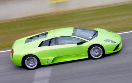 A bright green sports car with a sleek design speeding down the road in a blurred motion.
