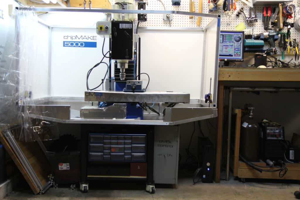 Well-equipped workshop with a CNCC router, various tools, and equipment on wooden workbenches.