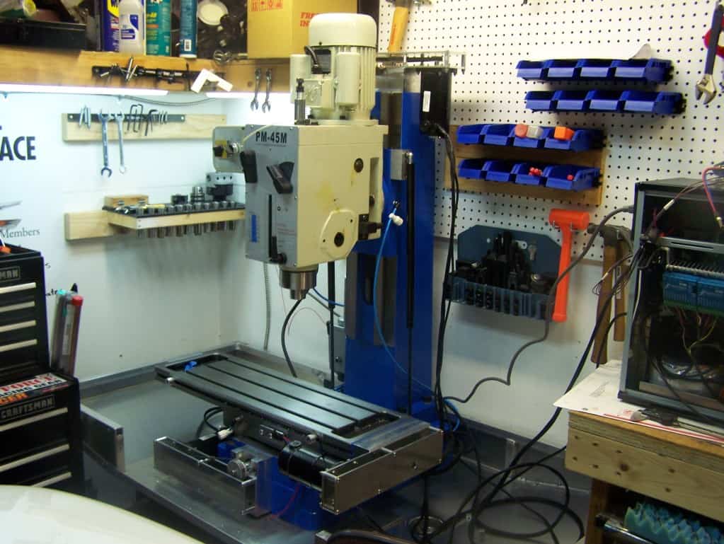 CNC milling machine in workshop setting with various tools and equipment.