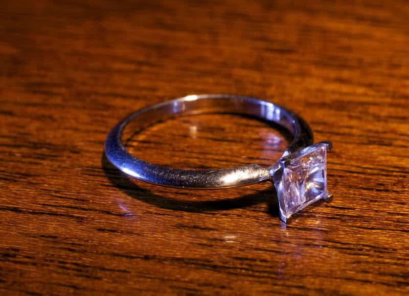 Silver ring with diamond or gemstone on wooden surface