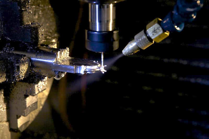Metalwork machining operation, milling machine with cutting tool and metal workpiece.