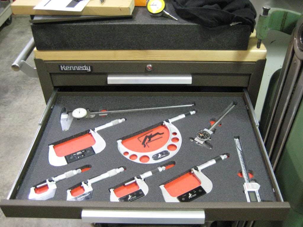 Precision measuring tools: calipers, micrometers, gauges, neatly organized in a box case.