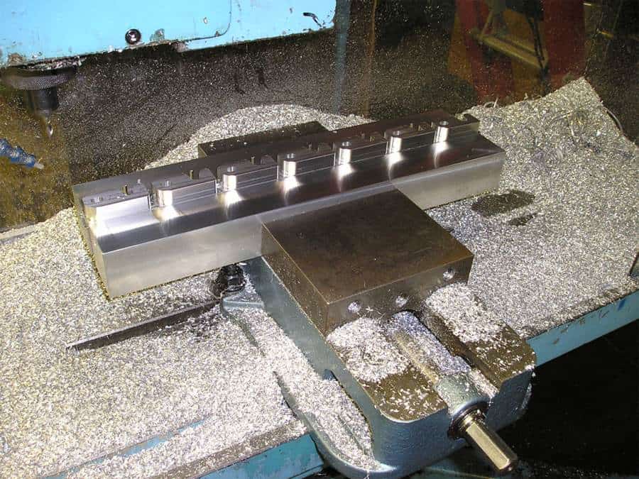 Large metal part with cylindrical protrusions on workbench in industrial setting.