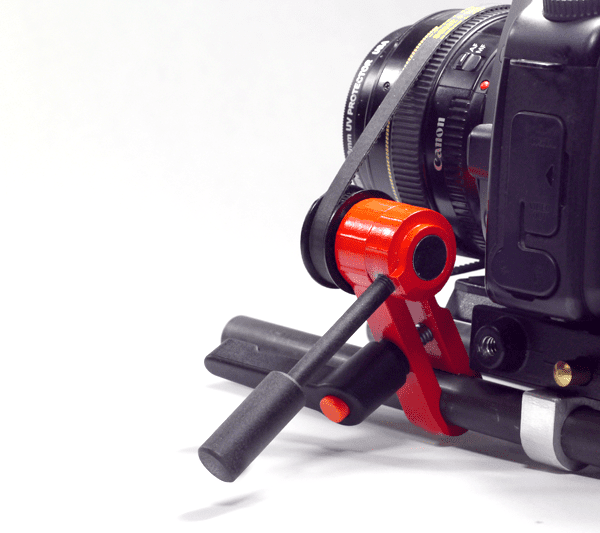 A black camera with lens and red/black device with black handles.