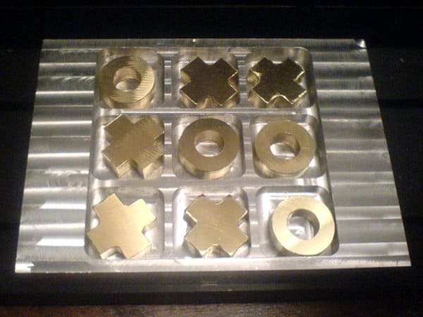 Clear plastic Tic-Tac-Toe board with gold pieces.