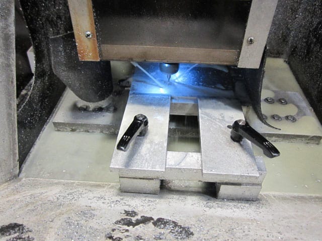 Industrial machinery part with two black levers, silver metal, gray background, dusty.