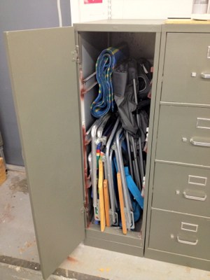 Gray vertical locker with open door showing organized collection of tools and equipment.