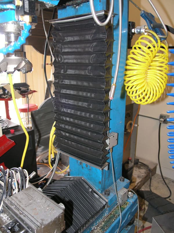 Industrial machine with black components and yellow wires in a workshop or manufacturing setting.