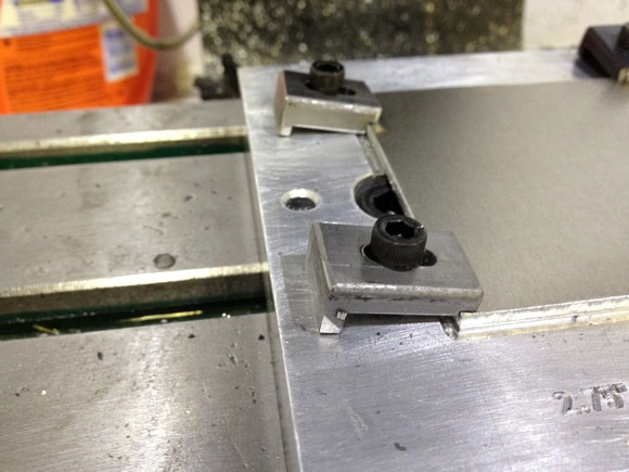 Metal object with silver surface, small black knob, and central hole.