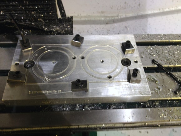 Metalworking machine part with two circular recesses on flat rectangular base.