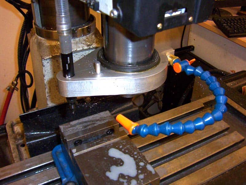 Metalworking machine with tools and equipment in background, featuring levers, handles, and a blue hose.