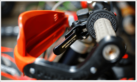 Black lever with white text, possibly made of plastic or metal, on a machinery in a workshop setting.