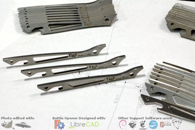 Metal bottle openers with hole in center, arranged on white surface, featuring different designs.