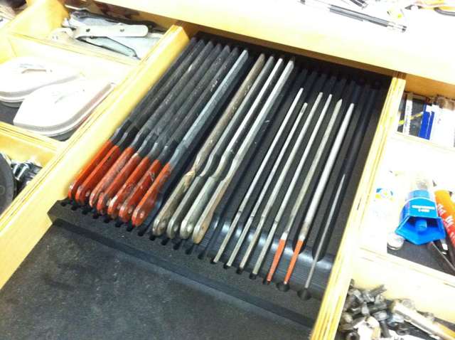 Yellow cabinet drawer with various tools and a black divider strip.