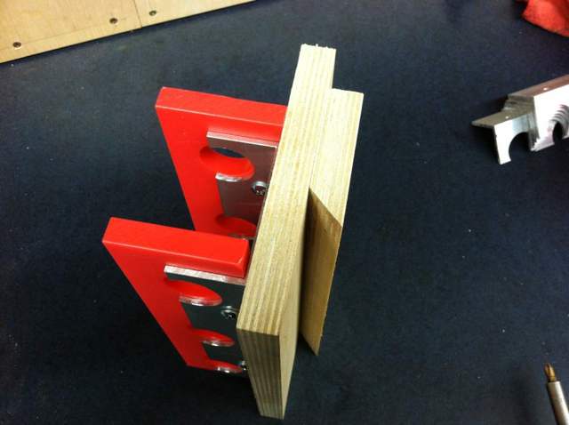 A French cleat with two parallel arms and holes at one end attached to wood.