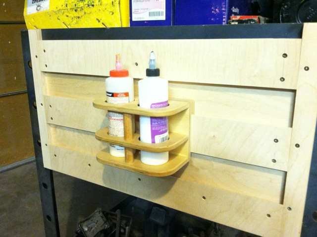 A wooden shelf with various bottles and containers on a workbench or table.