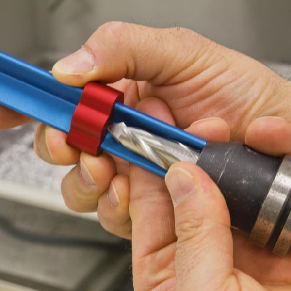 Person's hands holding a blue tool with red band for machining or metal fabrication.