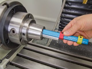 Hand holding a tool with blue handle and yellow strap near a metal object.