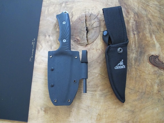 Black handled Gerber knife in black nylon sheath on wooden surface.