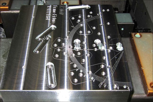 A shiny metal fixture with various holes and protrusions.