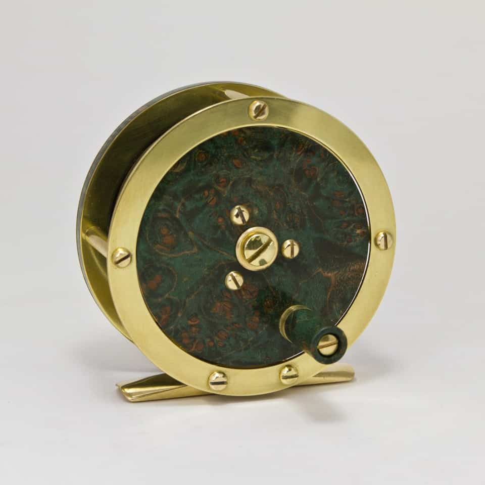 Vintage brass fishing reel with green patina.