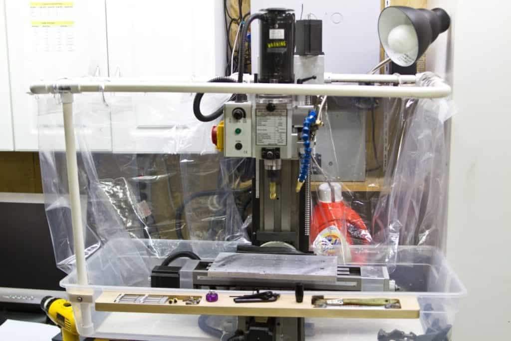 Industrial milling machine with plastic sheeting containment, controls and levers.