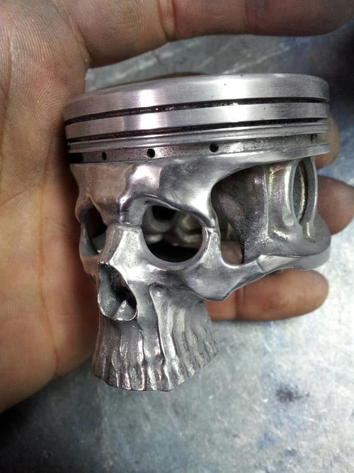 A silver piston with a skull-shaped design featuring holes for the eyes and teeth.