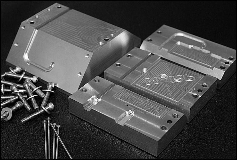 Close-up photograph of metal parts with screws and bolts on a black leather surface.