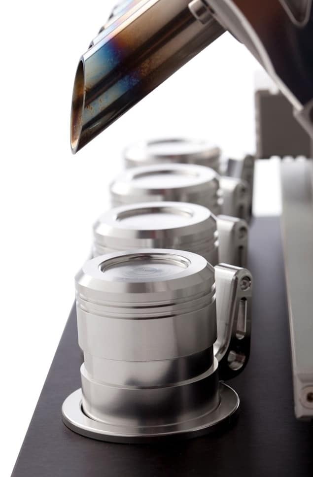 Silver stainless steel cups with handles on a black surface.