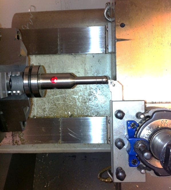 Metalworking lathe in industrial setting with metal parts and cylindrical piece on bed.