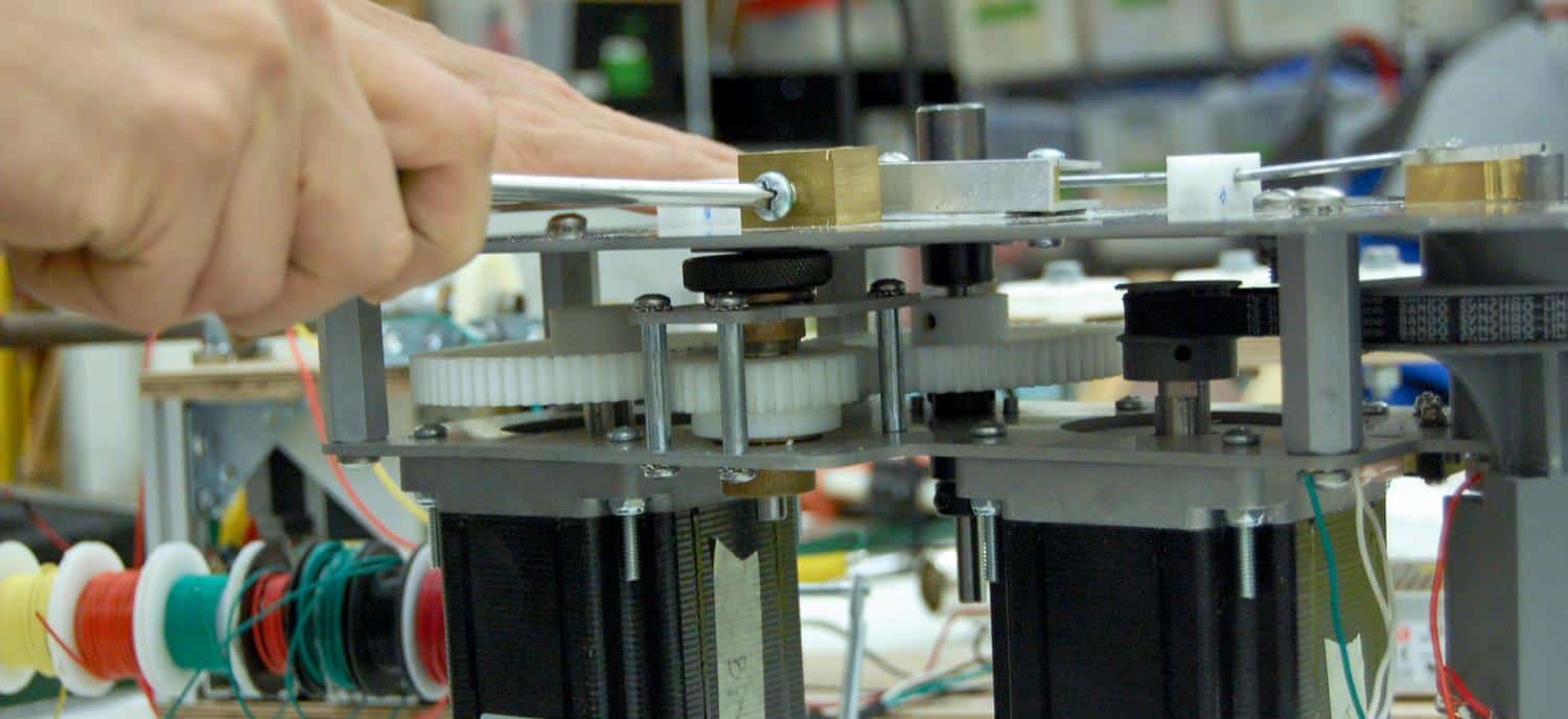 A person's hand reaches out to touch a complex electrical device with multiple wires and components.