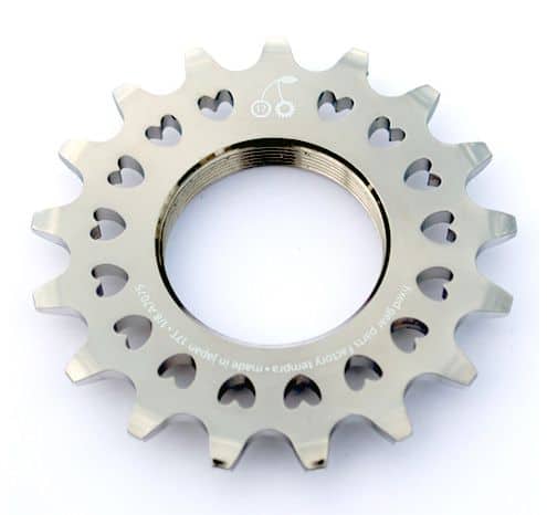 Metal cog with heart-shaped cutouts and engraved inscription on light-colored metal.