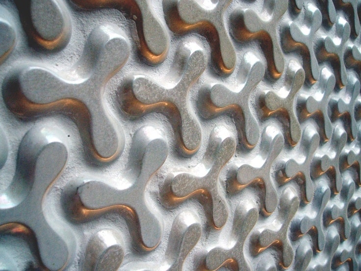 Close-up of metallic surface with embossed, interconnected rounded pattern in silver with copper accents.