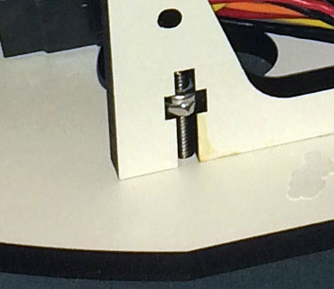 White plastic object with captive metal nut attached.