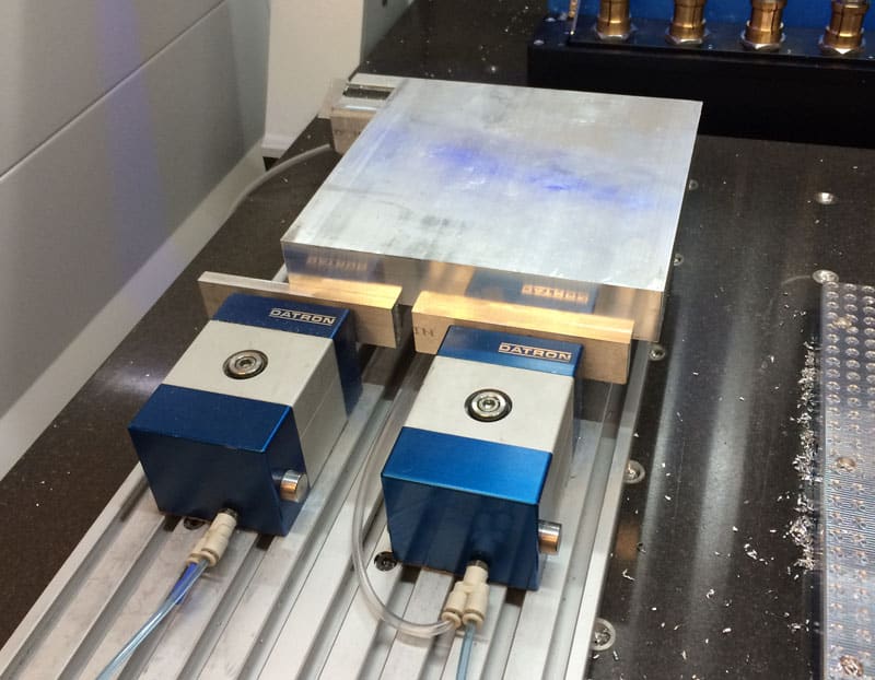 Two Datron vises on a workbench, showcasing precision and functionality in machining applications.