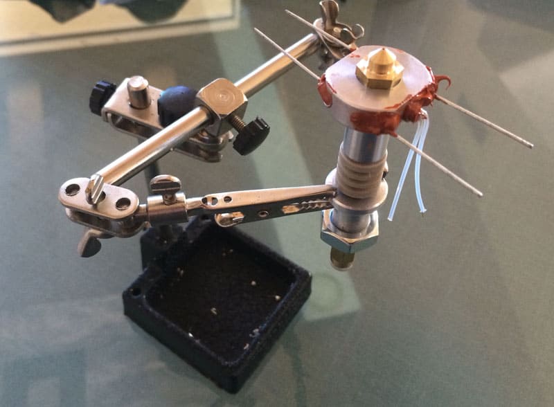 Metal tool with adjustable arms and black knobs on a grey surface.