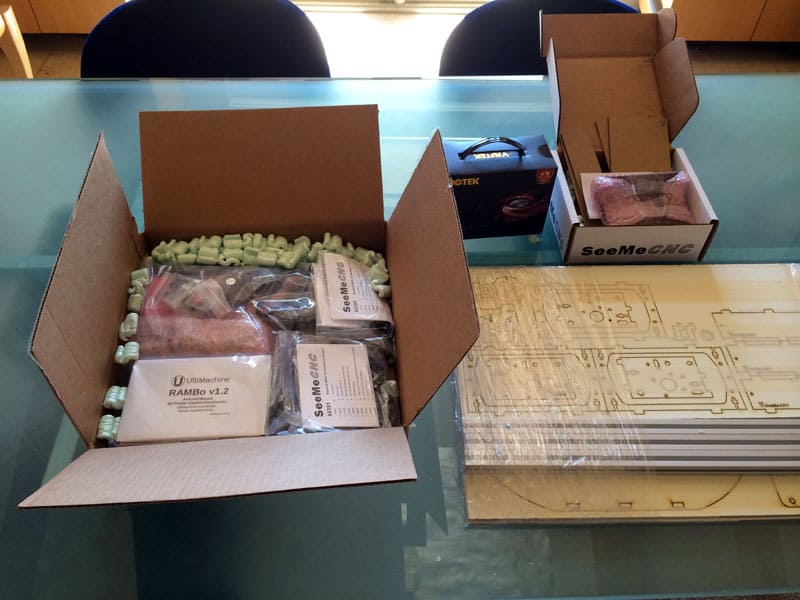 Cardboard box with plastic-wrapped contents, including RAMBO v1.2 and SeeMeCNC.
