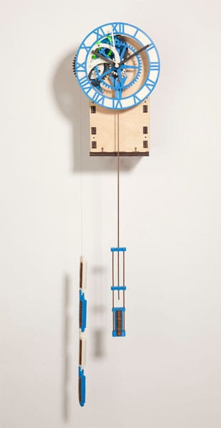 Wooden clock with blue Roman numerals and gears on a white wall.