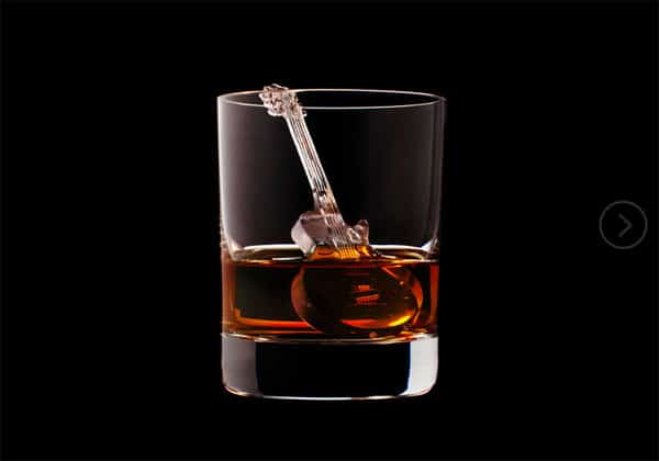 Amber-colored liquid in a glass with etched guitar design.