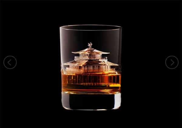 Amber-colored liquid in a glass with an etched pagoda design on a black background.