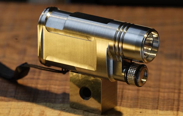 Shiny metallic cylindrical object with flat surface and intricate design features on a metal stand.