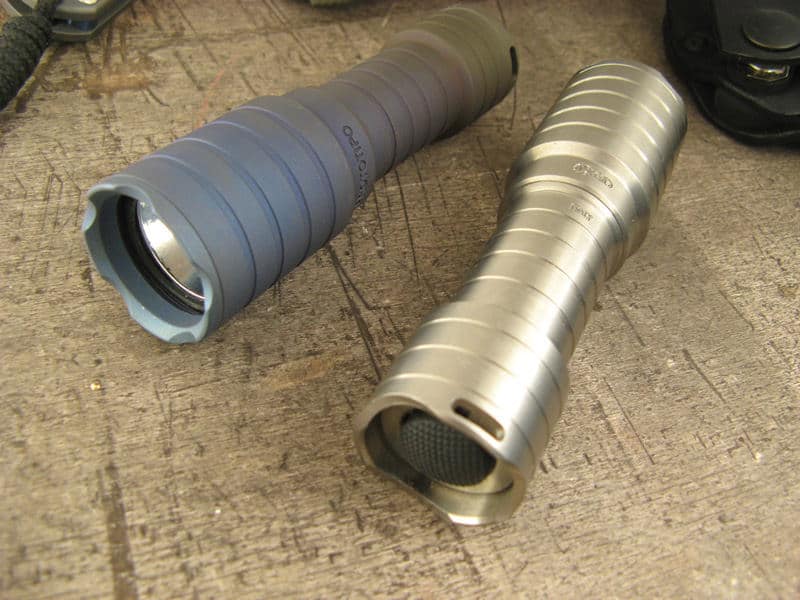 Two cylindrical objects with rounded ends containing small silver objects inside on a metal or plastic surface.