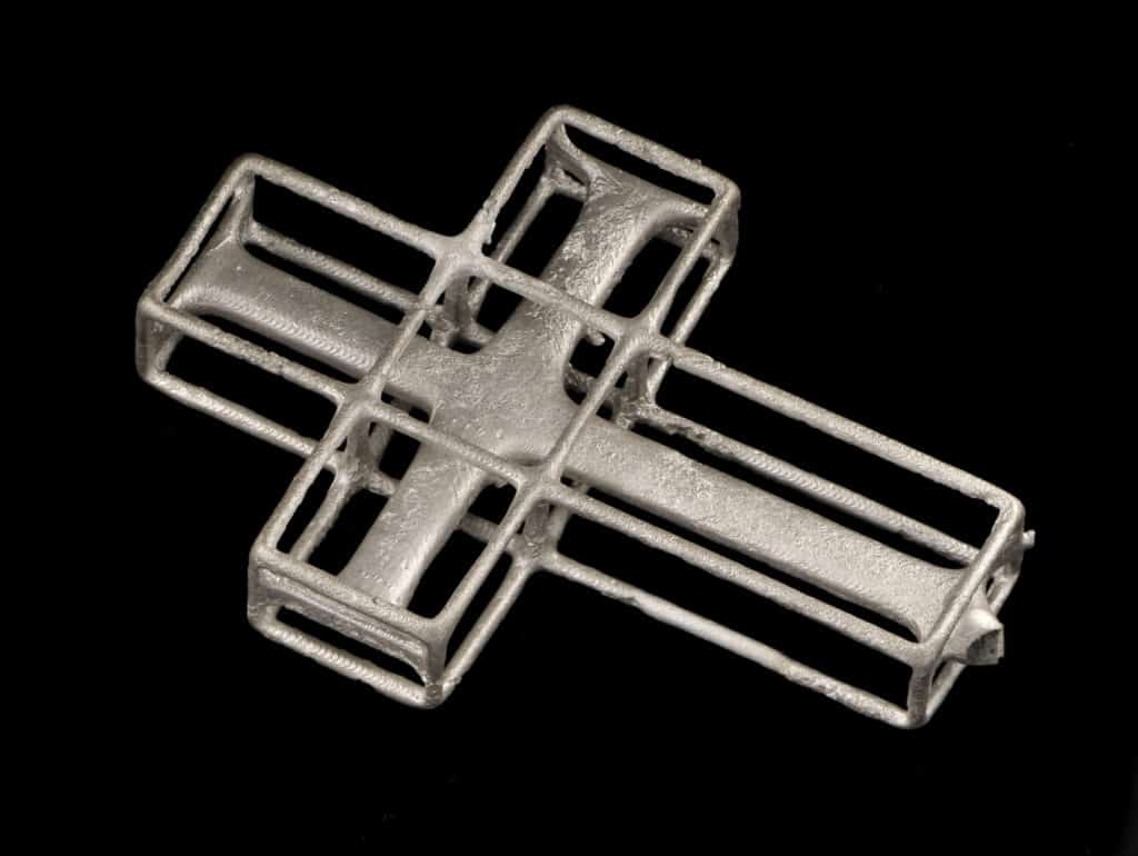 Silver cross casting on a plain background.